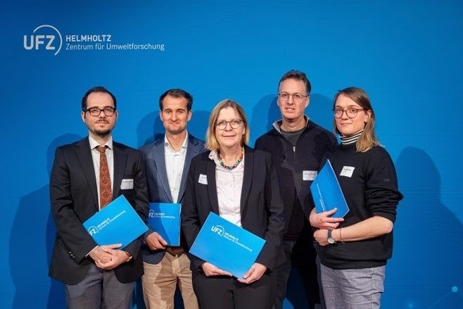 Fünf Personen mit blauen UFZ-Mappen vor einer blauen Bühnenwand